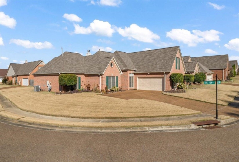 View of front of house with brick siding, driveway, a shingled roof, and a front lawn