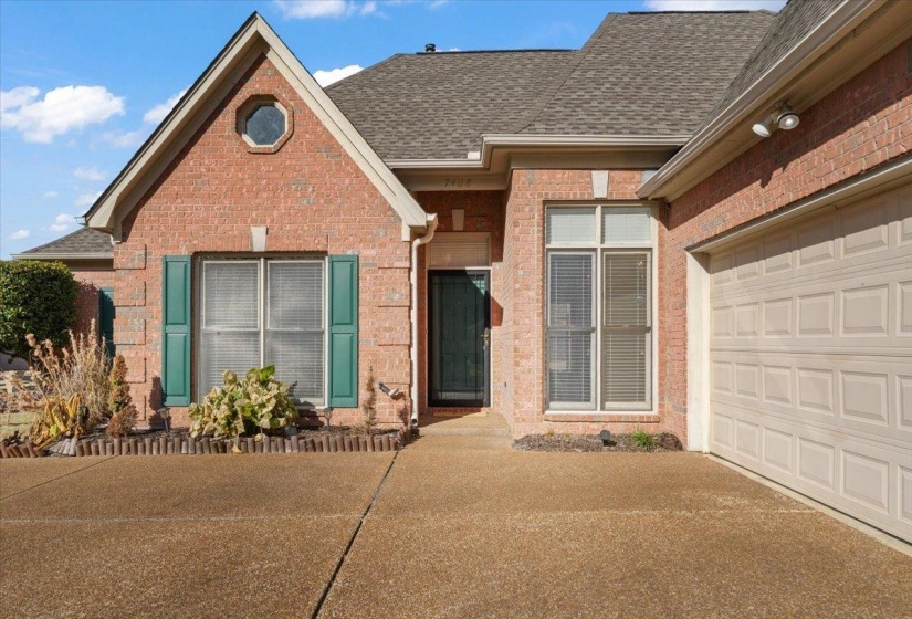 View of front of house with brick siding, a shingled roof, a garage, and driveway