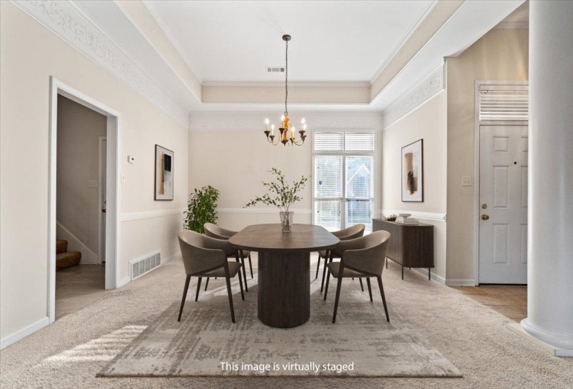 Dining area featuring a raised ceiling, a chandelier, stairs, ornamental molding, and light colored carpet