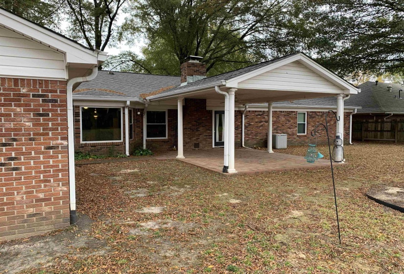 Rear view of property featuring a patio, a chimney, and brick siding