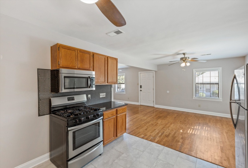 Kitchen with appliances with stainless steel finishes, a ceiling fan, brown cabinetry, and plenty of natural light