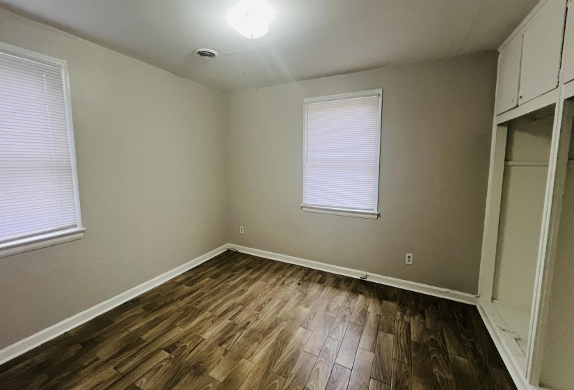 Unfurnished bedroom with dark wood-style floors and a closet