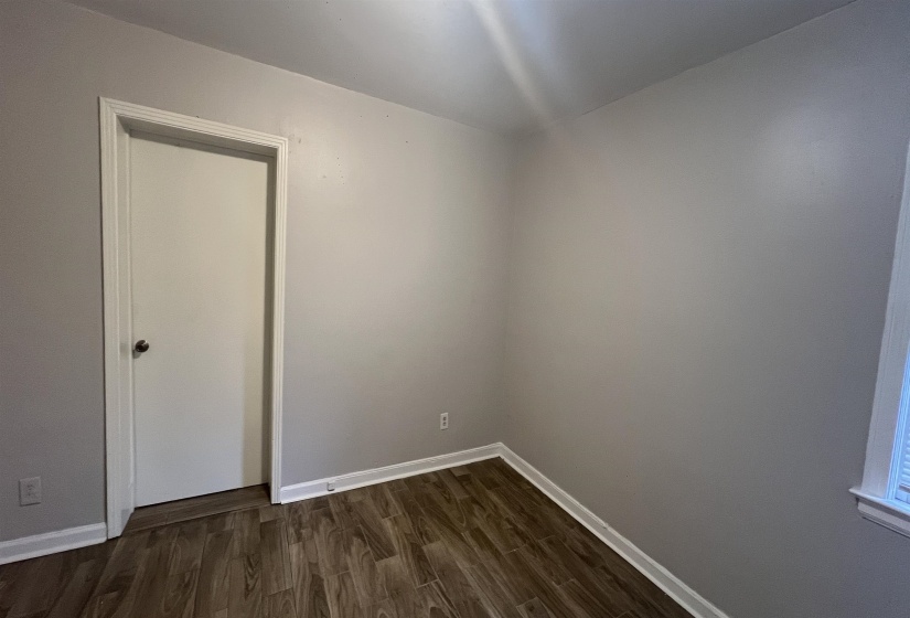 Spare room featuring dark wood-style floors and baseboards