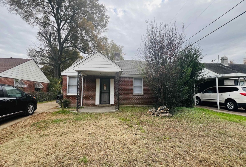 View of front of property with a front yard, brick siding, and a chimney