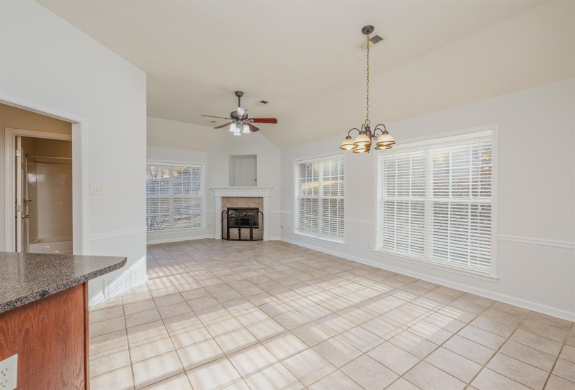 Hearth room with light tile flooring, ceiling fan, lofted ceiling, a tile fireplace, and a chandelier