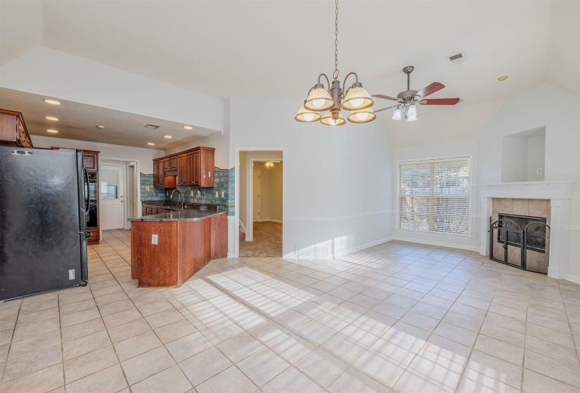 Hearth room with open floor plan, freestanding refrigerator, light tile floors, decorative backsplash, and hanging light fixtures