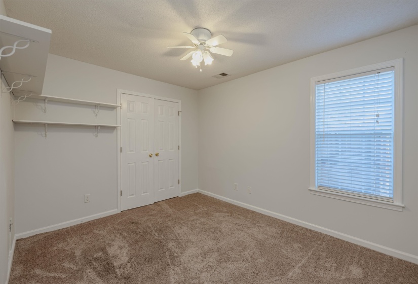 Bedroom 2 downstairs featuring carpet floors, a ceiling fan, and a closet