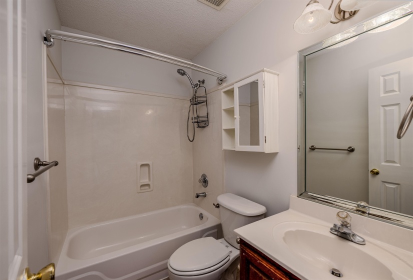 Bathroom featuring washtub / shower combination, a textured ceiling, and vanity