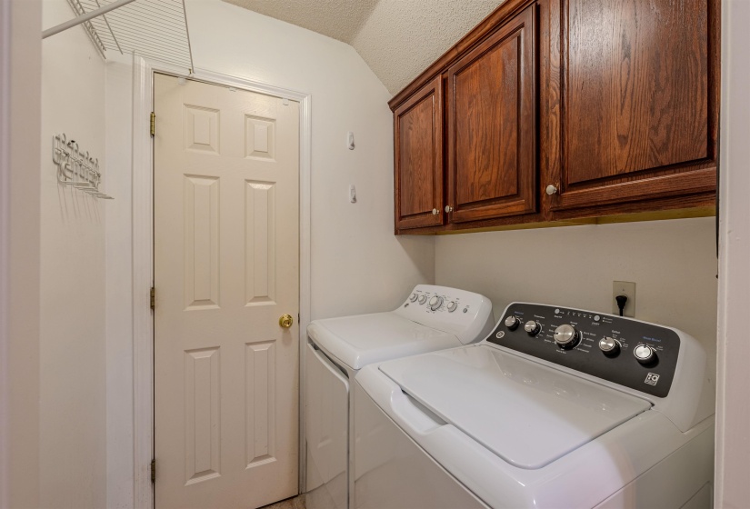 Laundry room with a textured ceiling, cabinet space, washing machine and dryer, and vaulted ceiling
