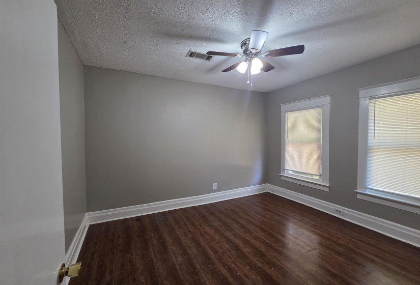Empty room featuring dark wood-style floors, a textured ceiling, and a ceiling fan