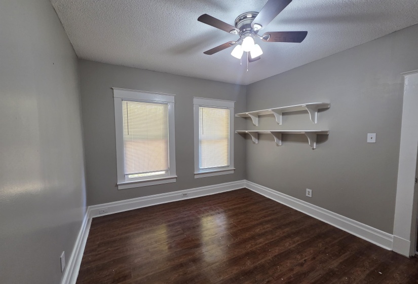 Spare room with dark wood-type flooring, a textured ceiling, and ceiling fan