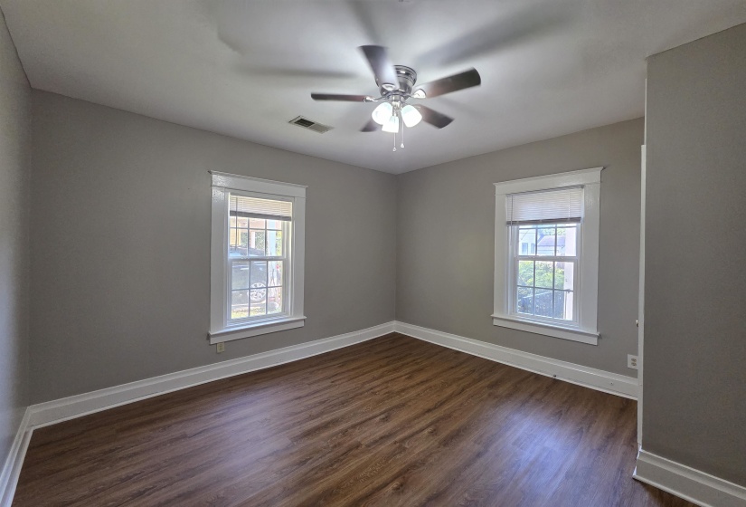 Empty room featuring dark wood-type flooring, healthy amount of natural light, and ceiling fan