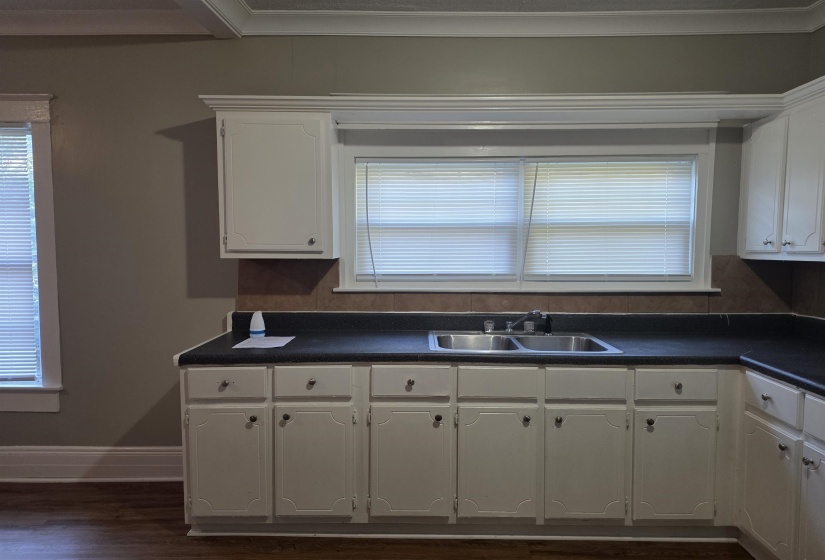 Kitchen featuring healthy amount of natural light, dark countertops, white cabinets, and dark wood-type flooring
