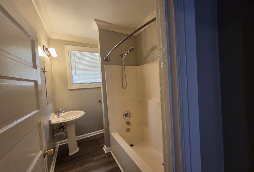 Full bathroom with shower / tub combination, dark wood-style floors, and crown molding