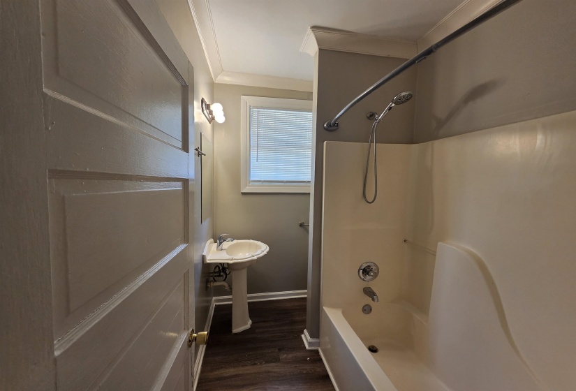 Full bath with bathtub / shower combination, dark wood finished floors, and ornamental molding