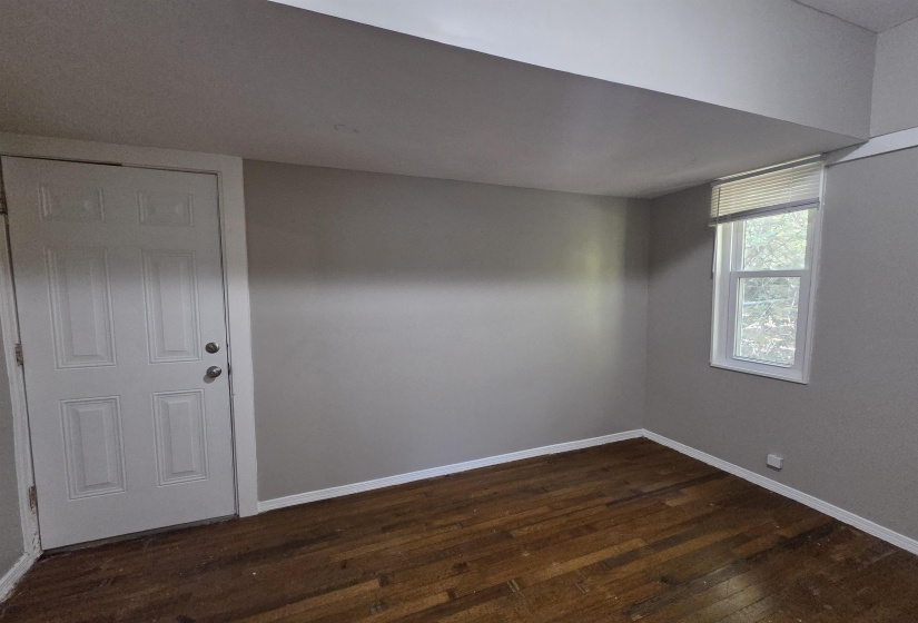 Empty room with dark wood-type flooring and baseboards