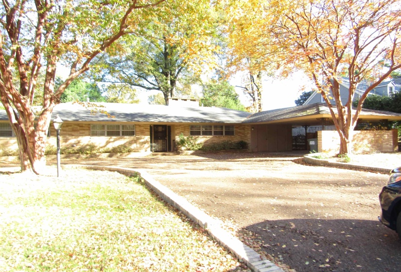 Ranch-style home with dirt driveway and an attached carport