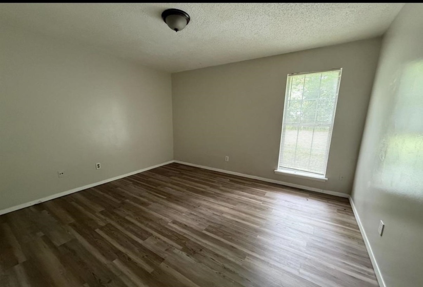 Empty room with a textured ceiling and dark wood-style floors