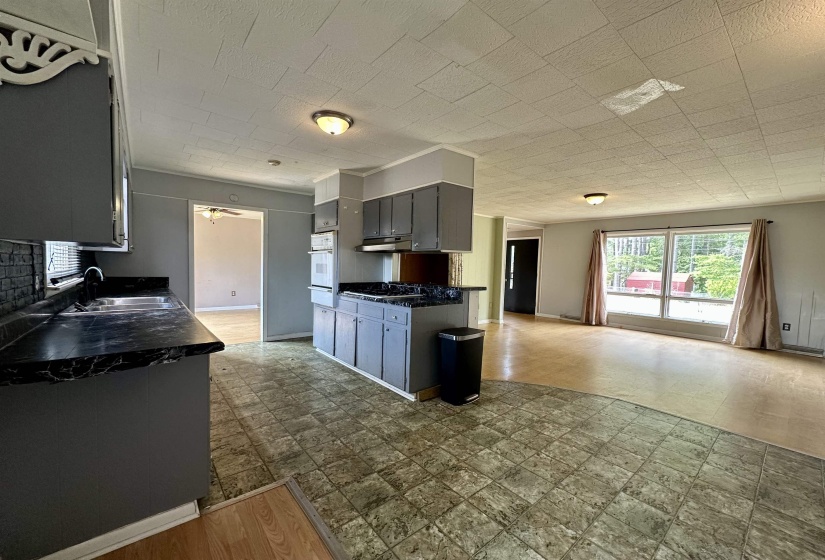 Kitchen featuring dark countertops, gray cabinetry, oven, light wood-style floors, and a warming drawer