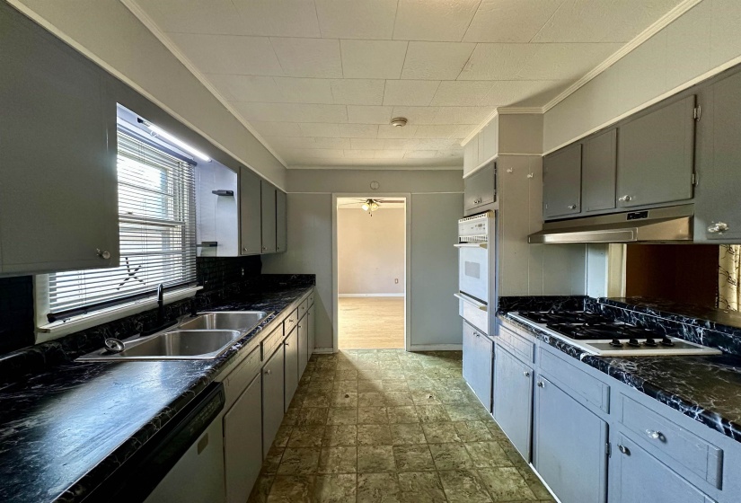 Kitchen with dark countertops, gray cabinetry, white appliances, ornamental molding, and decorative backsplash