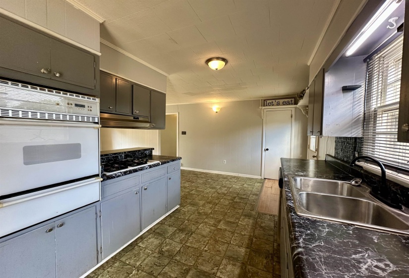 Kitchen with dark countertops, ornamental molding, white appliances, a warming drawer, and gray cabinets