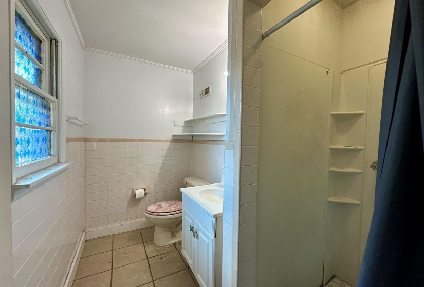 Full bath with light tile patterned floors, vanity, ornamental molding, tile walls, and a shower stall