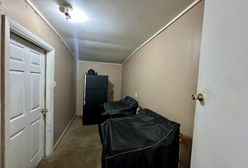 Bedroom featuring freestanding refrigerator and vaulted ceiling