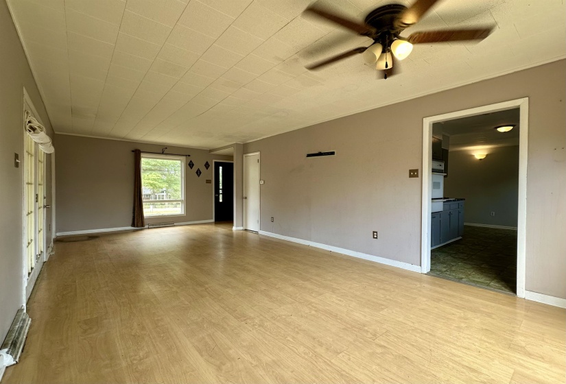 Empty room with light wood finished floors, ceiling fan, and ornamental molding