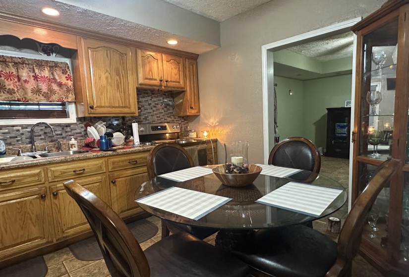 Kitchen featuring a textured ceiling, brown cabinetry, decorative backsplash, electric range, and light stone counters