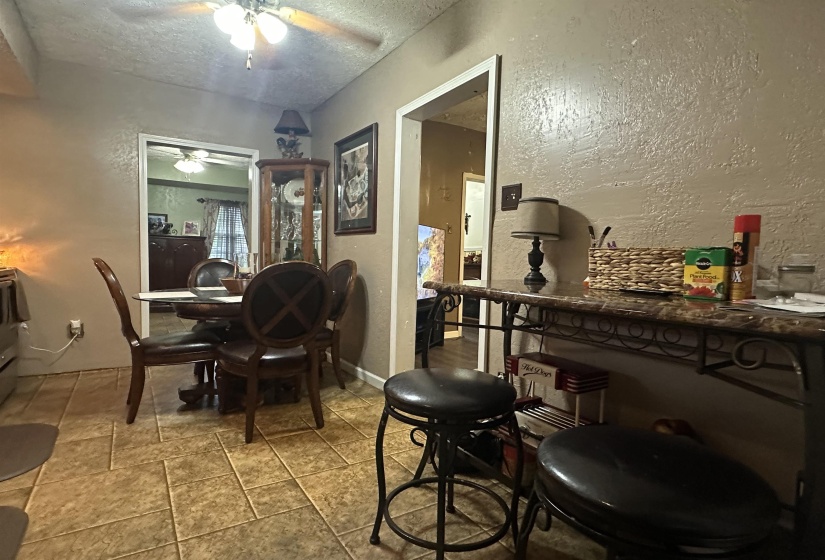 Dining space with a textured wall, a textured ceiling, and a ceiling fan