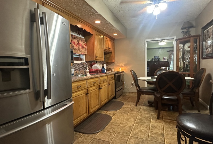 Kitchen with stainless steel appliances, brown cabinetry, recessed lighting, a textured ceiling, and light tile patterned floors