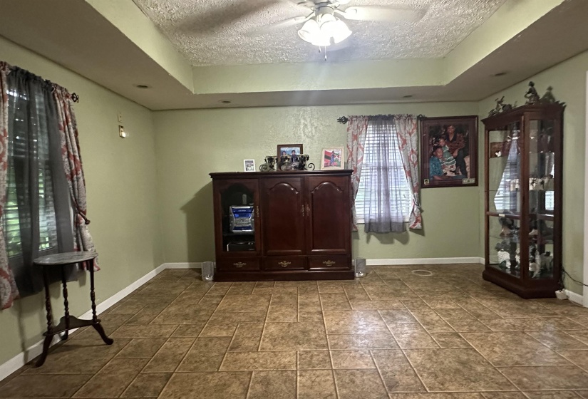 Interior space featuring a textured ceiling, a raised ceiling, and ceiling fan