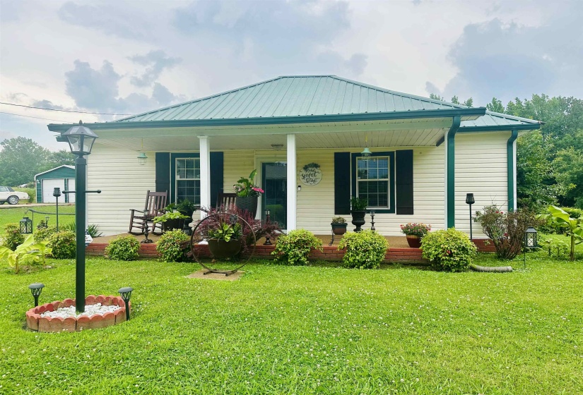 View of front of property featuring a porch, a metal roof, and a front yard
