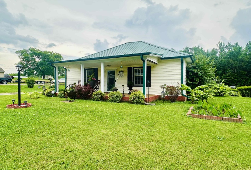 View of front of home with covered porch, a front lawn, and a metal roof