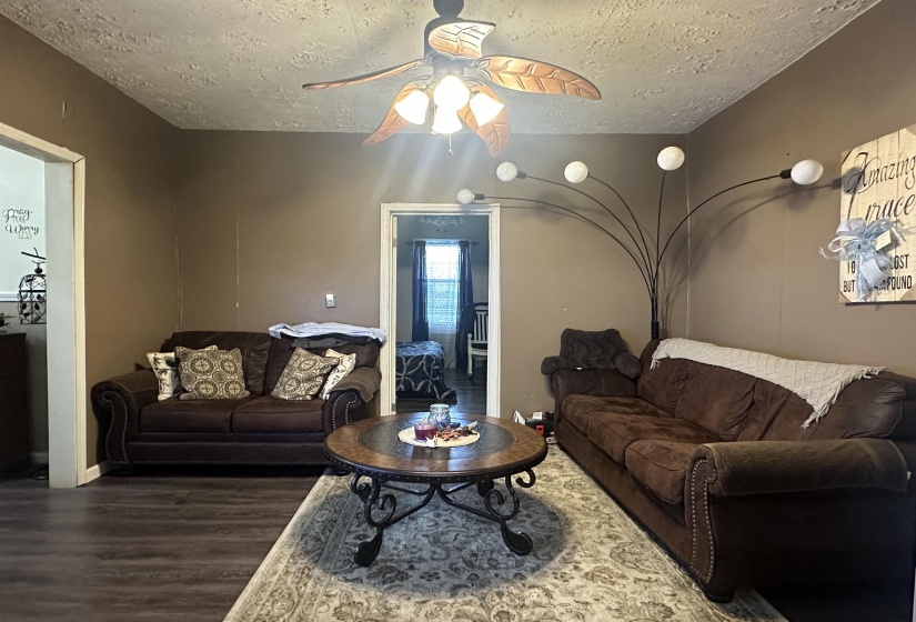 Living room with wood finished floors, ceiling fan, and a textured ceiling