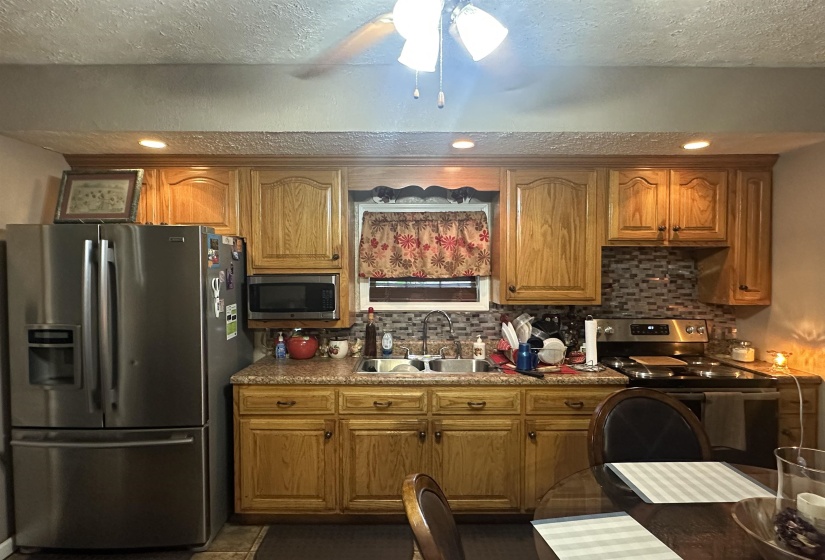 Kitchen featuring stainless steel appliances, brown cabinetry, tasteful backsplash, recessed lighting, and a textured ceiling
