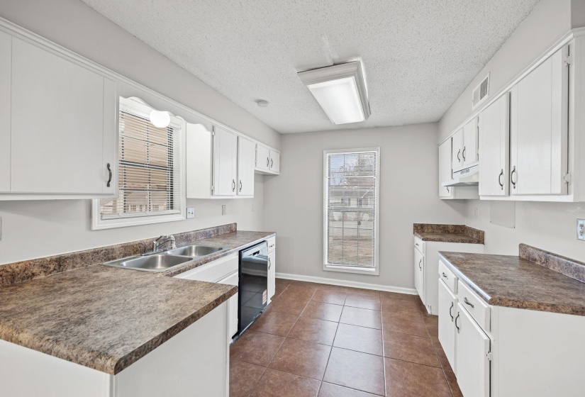 Kitchen with dark countertops, white cabinets, a textured ceiling, and dark tile patterned flooring