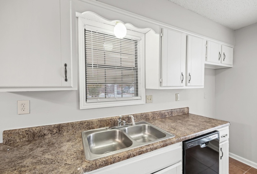 Kitchen featuring black dishwasher, white cabinets, dark tile patterned floors, a textured ceiling, and dark countertops