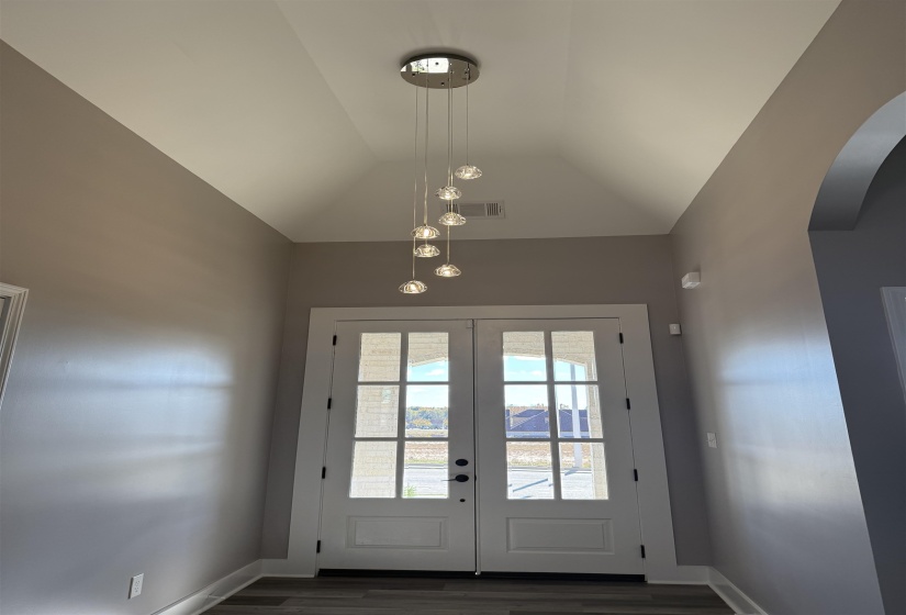 Entryway with french doors, wood finished floors, vaulted ceiling, and arched walkways