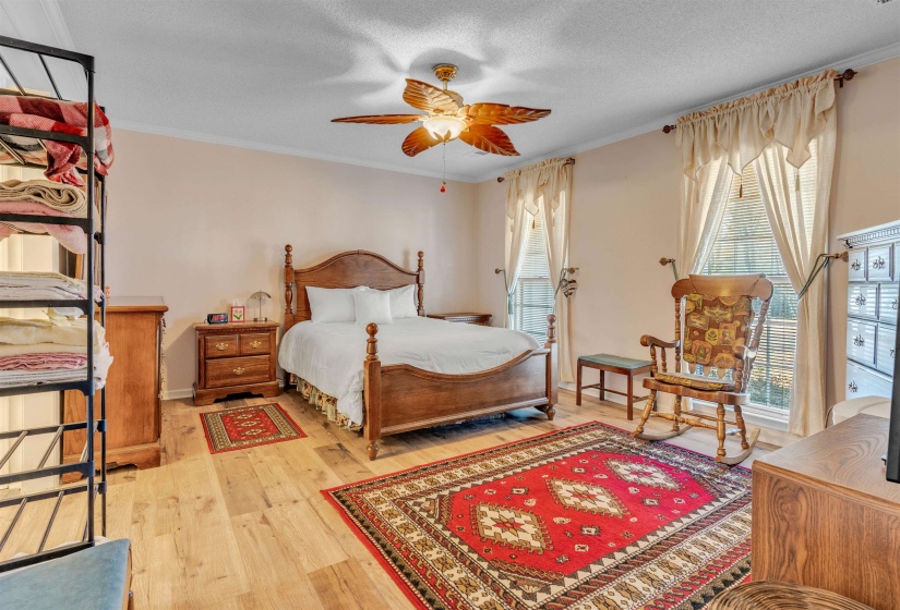 Bedroom featuring wood finished floors, crown molding, a textured ceiling, and a ceiling fan