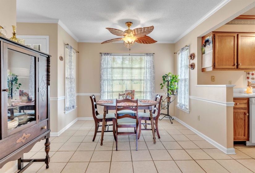 Dining area featuring light tile patterned floors, a textured ceiling, ornamental molding, and ceiling fan