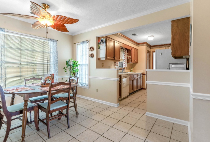 Dining space featuring a textured ceiling, crown molding, ceiling fan, and light tile patterned floors