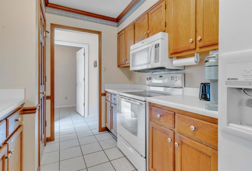 Kitchen with ornamental molding, white appliances, light countertops, and light tile patterned floors