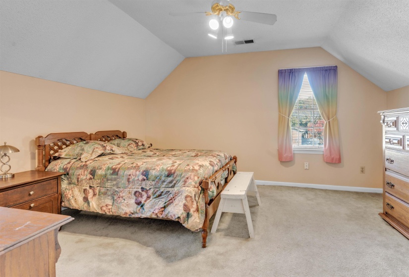 Bedroom featuring lofted ceiling, light colored carpet, ceiling fan, and a textured ceiling