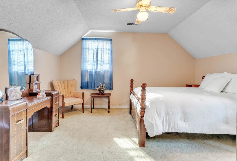 Bedroom featuring light colored carpet, a textured ceiling, vaulted ceiling, and a ceiling fan
