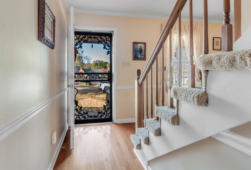 Entrance foyer featuring light wood finished floors, crown molding, and stairs