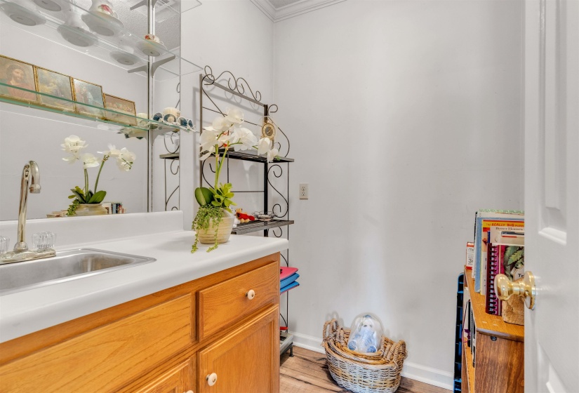 Bar featuring light countertops, light wood-style floors, brown cabinetry, and crown molding