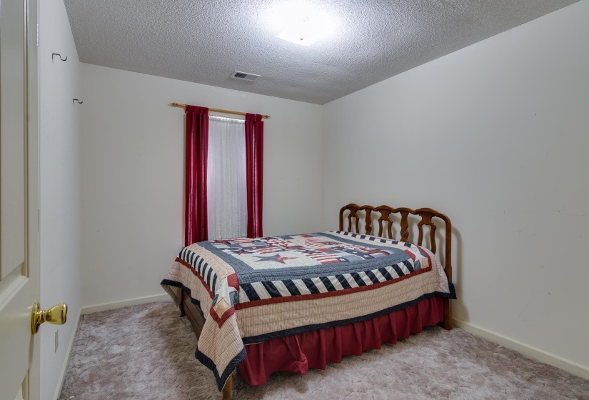 Bedroom featuring a textured ceiling and light carpet
