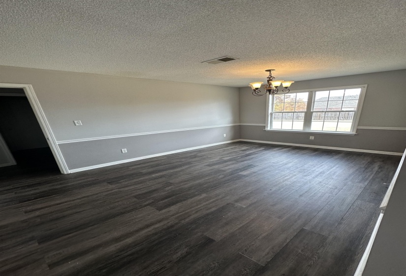 Unfurnished dining area featuring dark wood finished floors, a chandelier, and a textured ceiling