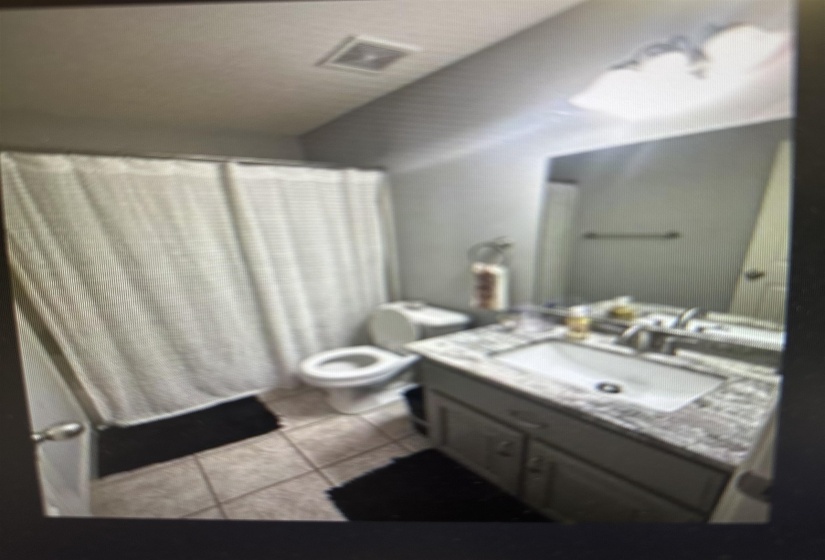 Full bathroom with a shower with shower curtain, vanity, and light tile patterned floors